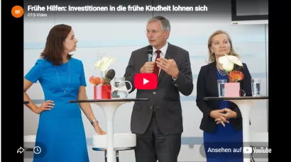 Vorschaubild eines Videos über den Nutzen Früher Hilfen. Zu sehen sind drei Personen bei einer Podiumsdiskussion. Titel des Videos: „Frühe Hilfen: Investitionen in die frühe Kindheit lohnen sich“.