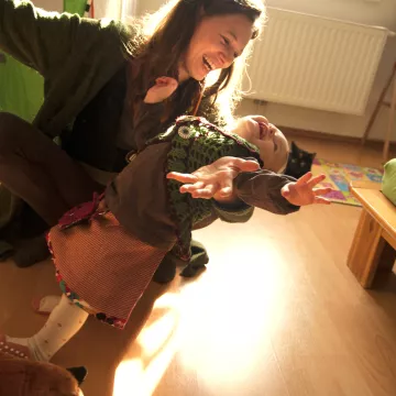 Erwachsene Person und Kleinkind beim gemeinsamen Spiel. Symbolbild für Unterstützung von Familien und frühe Förderung.